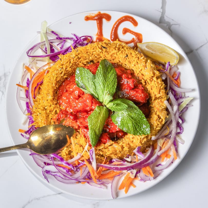 Indian Garden's chicken tikka biryani with mint, lemon, and a side of red onion and cabbage.