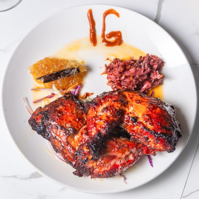 Indian Garden's grilled chicken with two sides and "IG" written in sauce on a white plate.