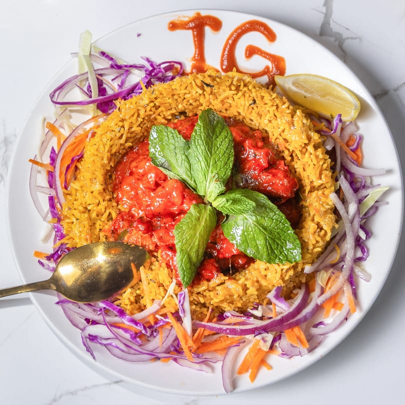 Indian Garden's chicken tikka biryani, garnished with mint, lemon, and a side of shredded vegetables.