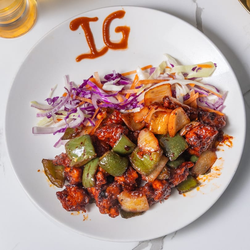 Indian Garden's chili chicken with bell peppers, onions, and a side of shredded cabbage salad.